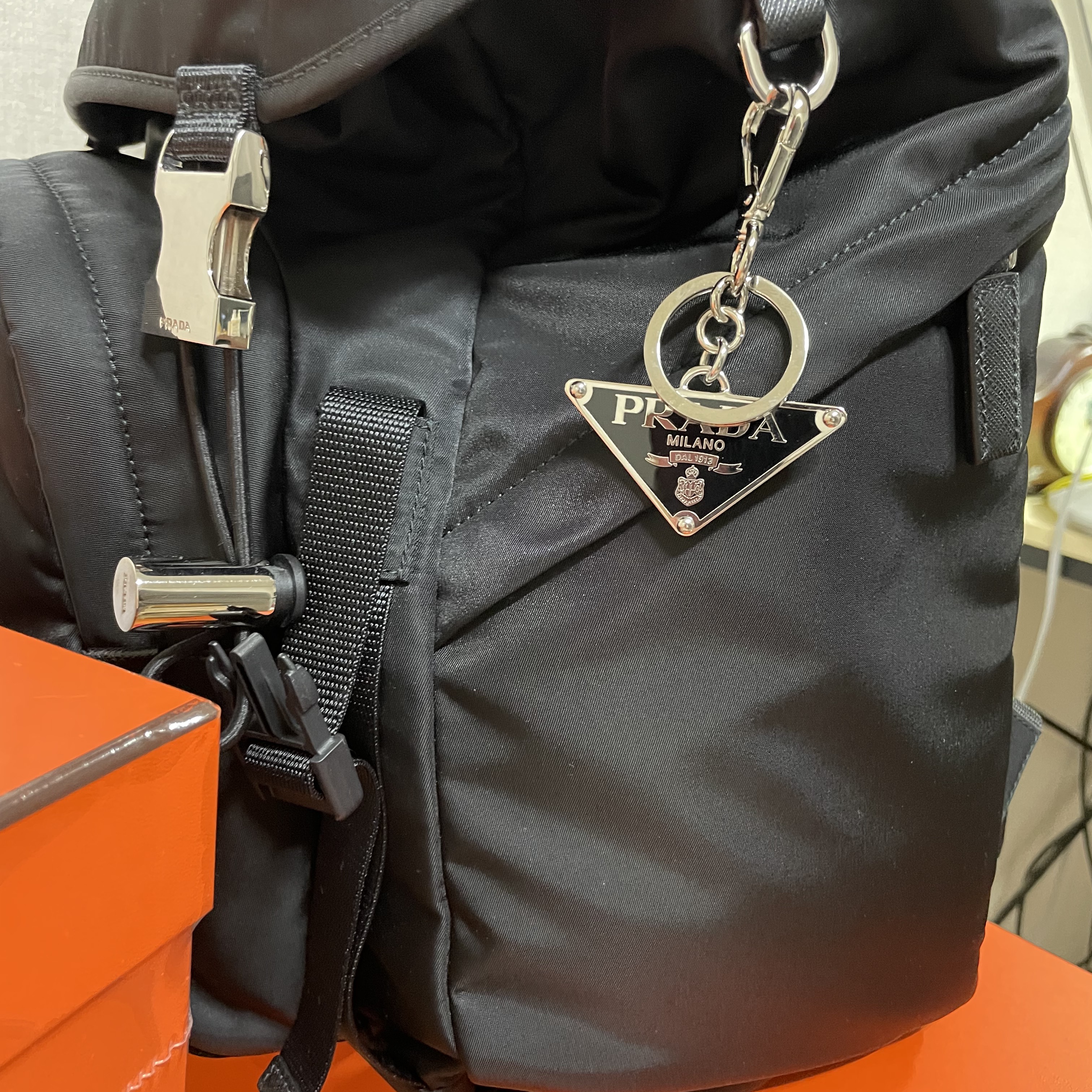 Prada Saffiano Leather Triangle Logo Keychain Black Silver, Prada Re-Nylon and Saffiano Leather Backpack Black 착용 스타일 - 3