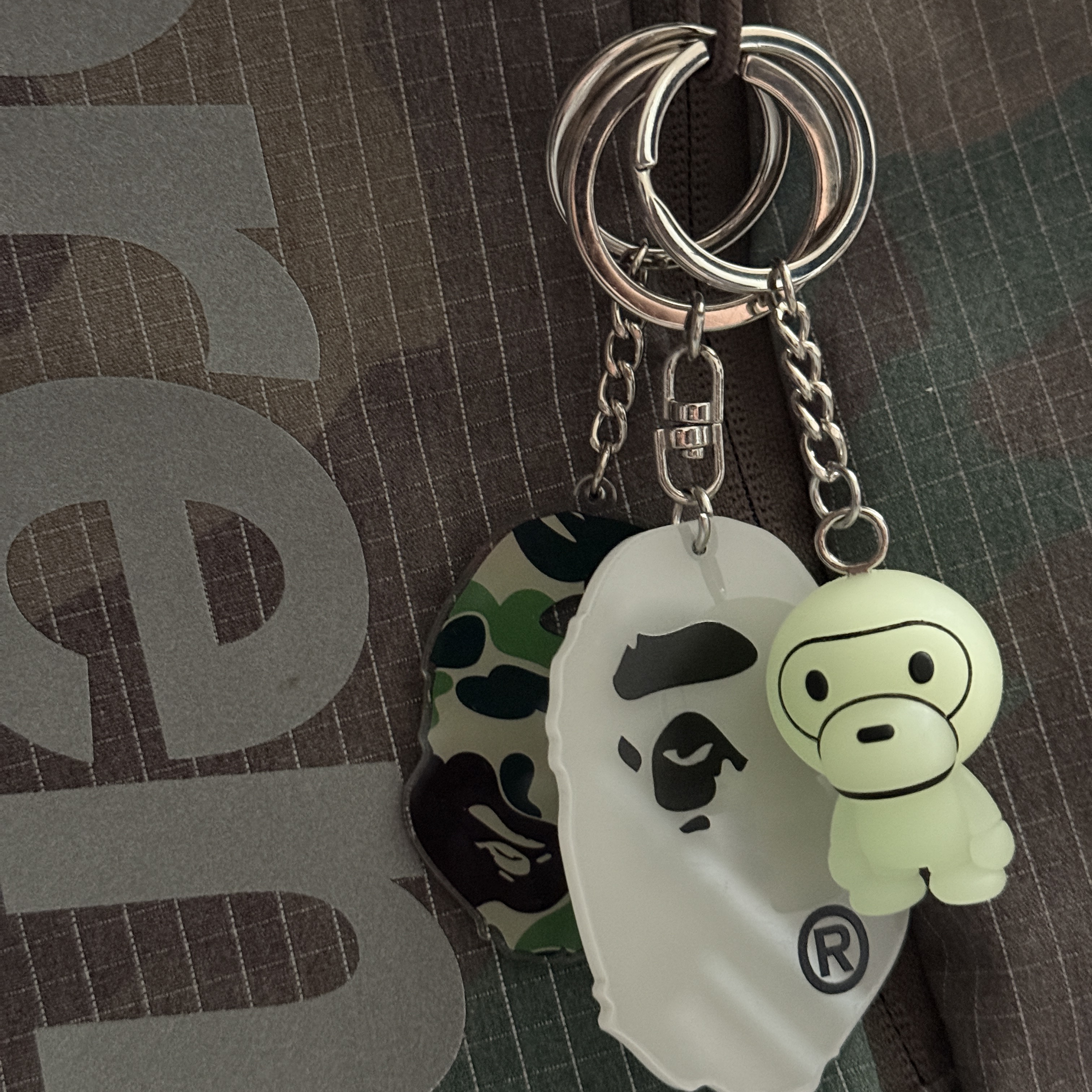 Supreme Backpack Woodland Camo - 24SS, BAPE Glow In The Dark Ape Head Keychain White Green 착용 스타일